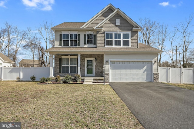 craftsman house featuring driveway, a gate, stone siding, fence, and a front yard