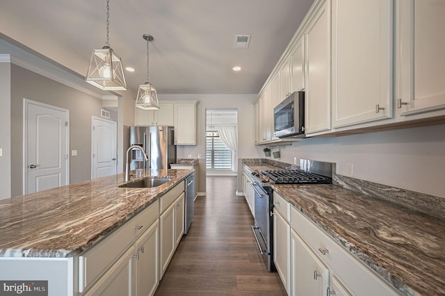 kitchen with visible vents, dark stone counters, dark wood-style floors, stainless steel appliances, and a sink