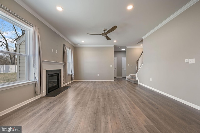 unfurnished living room featuring a glass covered fireplace, baseboards, and wood finished floors