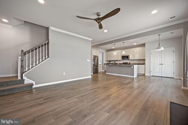 unfurnished living room with stairway, ornamental molding, baseboards, and dark wood-style flooring