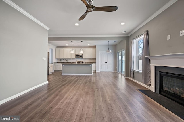 unfurnished living room with crown molding, baseboards, a fireplace with flush hearth, recessed lighting, and dark wood-style floors