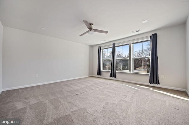 carpeted spare room with visible vents, ceiling fan, and baseboards