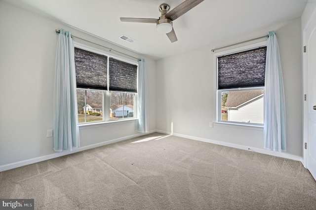 unfurnished room with carpet flooring, a healthy amount of sunlight, visible vents, and ceiling fan