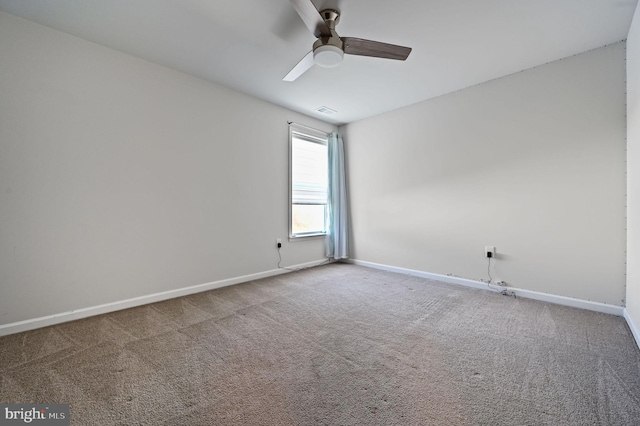 carpeted spare room featuring visible vents, baseboards, and a ceiling fan