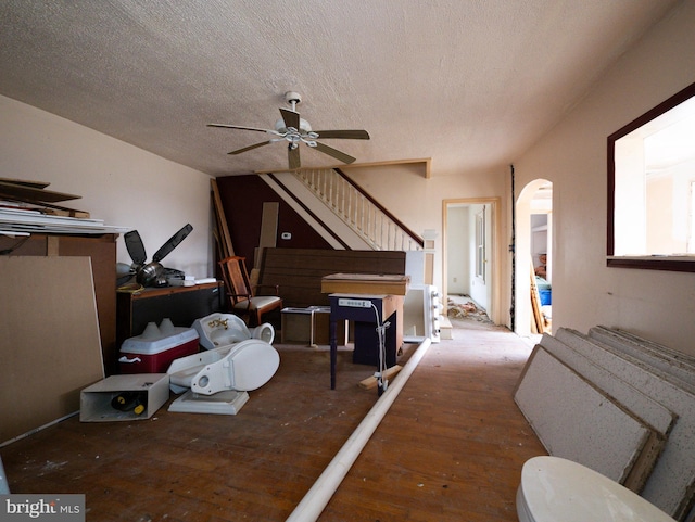 interior space featuring a ceiling fan, stairs, arched walkways, and a textured ceiling