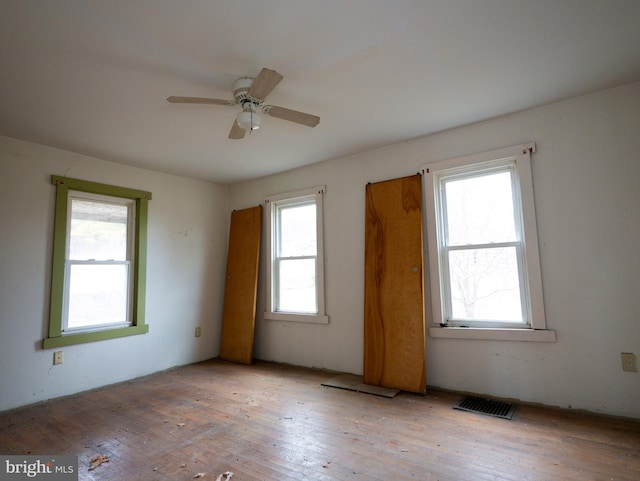 unfurnished room featuring wood-type flooring, visible vents, and a ceiling fan