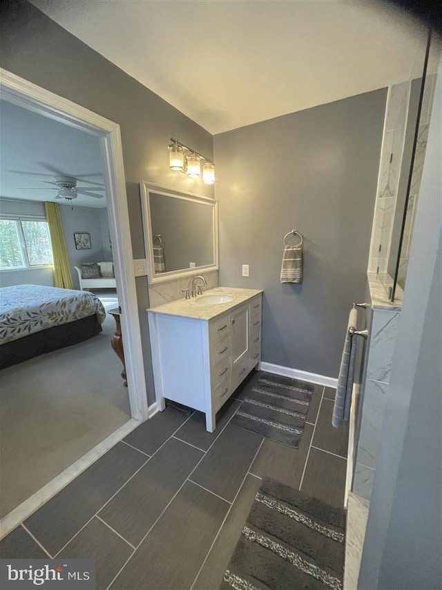 ensuite bathroom featuring ceiling fan, baseboards, connected bathroom, and vanity