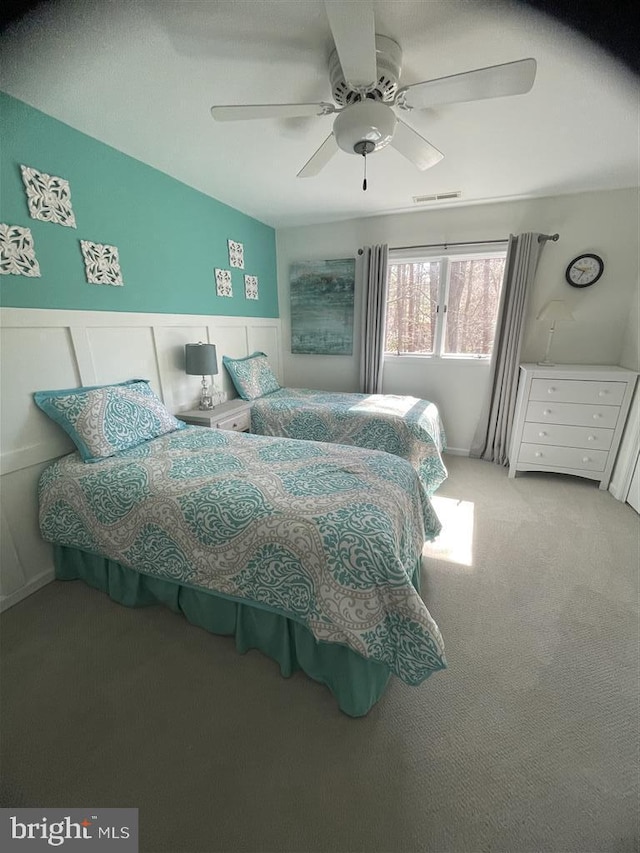 bedroom featuring visible vents, wainscoting, carpet flooring, and a ceiling fan