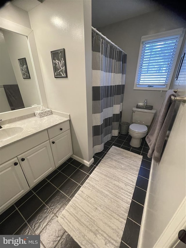 bathroom with a shower with curtain, vanity, toilet, and tile patterned floors