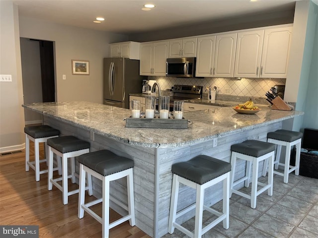 kitchen featuring stainless steel appliances, backsplash, visible vents, and white cabinetry