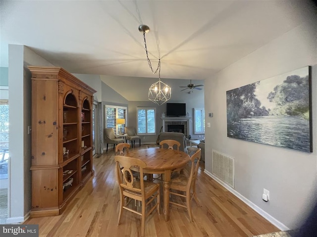 dining area featuring light wood-type flooring, baseboards, a fireplace, and visible vents