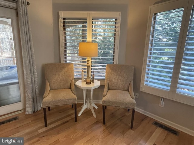 sitting room with a healthy amount of sunlight, visible vents, and wood finished floors