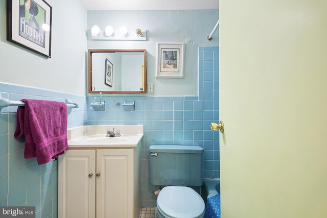 full bath featuring toilet, vanity, tile walls, wainscoting, and walk in shower