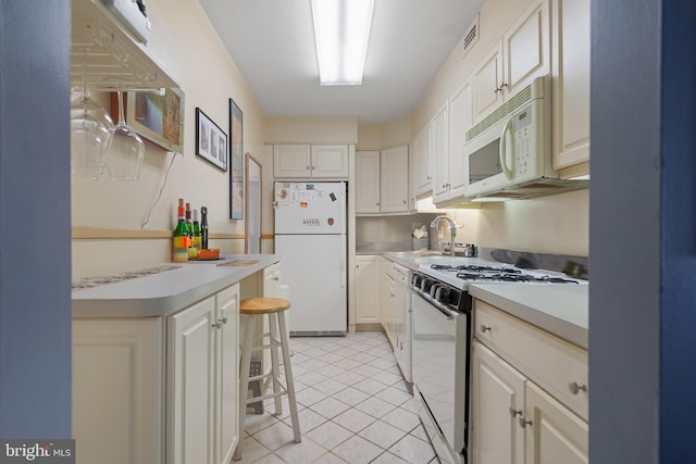 kitchen with white appliances, visible vents, white cabinets, light countertops, and a sink