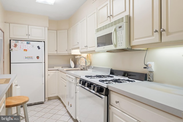 kitchen featuring white appliances, light countertops, a sink, and light tile patterned floors