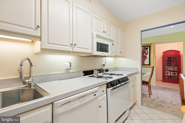 kitchen featuring light tile patterned floors, light countertops, white cabinetry, a sink, and white appliances