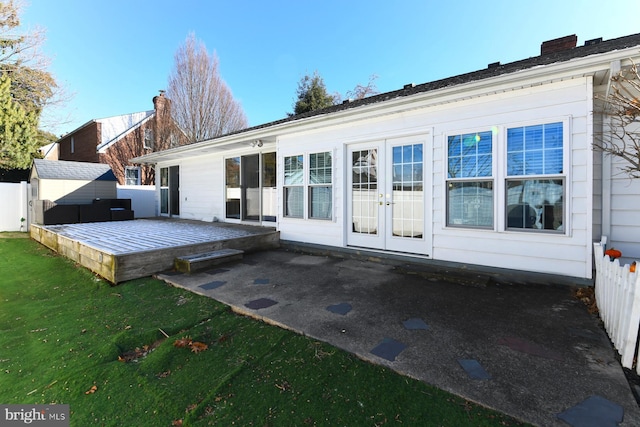 rear view of property featuring a chimney, french doors, a yard, and a deck