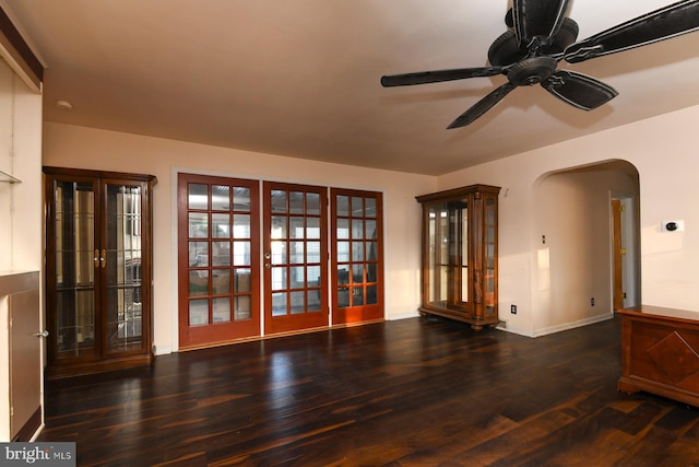 unfurnished room with ceiling fan, arched walkways, wood finished floors, and baseboards