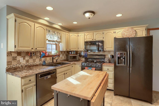 kitchen featuring black appliances, tasteful backsplash, a sink, and wooden counters