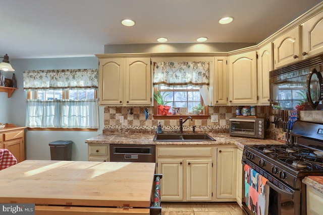 kitchen with butcher block countertops, cream cabinetry, a sink, and black appliances