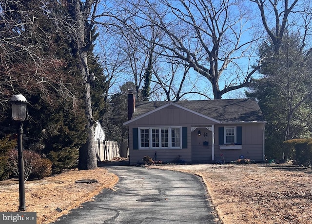 view of front of home with board and batten siding, driveway, and a chimney