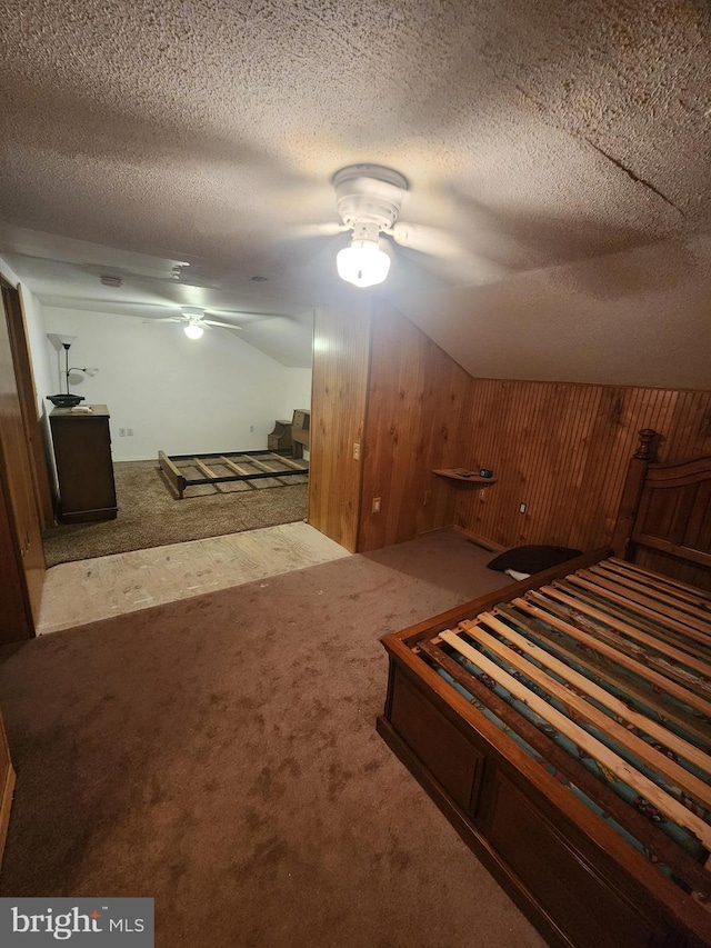 unfurnished bedroom with carpet, wood walls, a textured ceiling, and ceiling fan