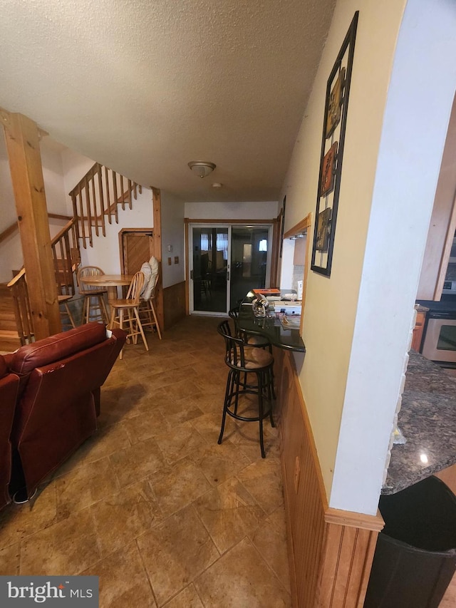 interior space with a wainscoted wall, a textured ceiling, and stairs