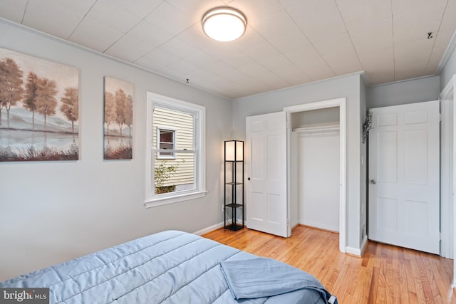 bedroom with a closet, light wood-style flooring, and baseboards