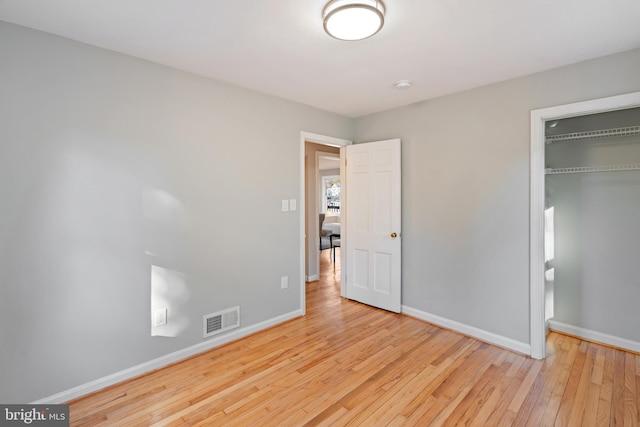 unfurnished bedroom featuring baseboards, a closet, visible vents, and hardwood / wood-style floors