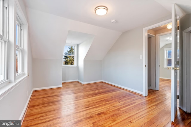 bonus room featuring light wood-style floors, vaulted ceiling, and baseboards