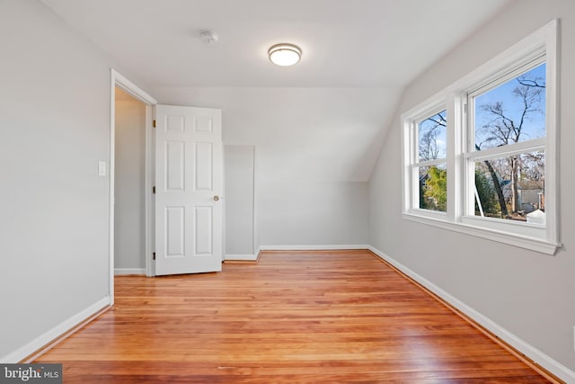 additional living space with vaulted ceiling, light wood-style flooring, and baseboards