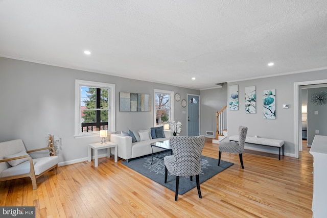 living room featuring light wood finished floors, stairs, baseboards, and a textured ceiling