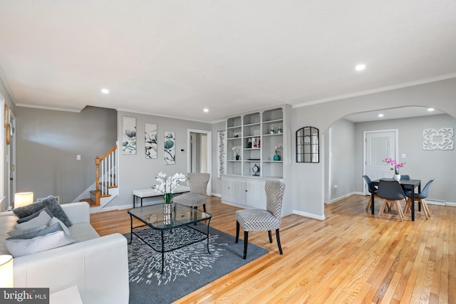 living room with arched walkways, stairway, light wood-type flooring, and baseboards