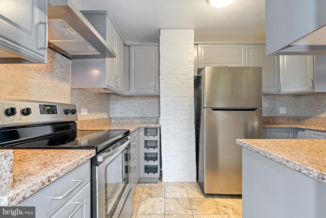 kitchen with wall chimney range hood, appliances with stainless steel finishes, backsplash, and gray cabinetry