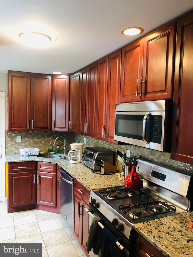 kitchen with a toaster, stainless steel appliances, decorative backsplash, a sink, and dark brown cabinets