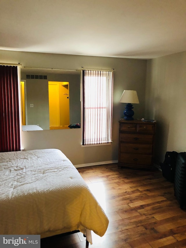 bedroom featuring baseboards, visible vents, and wood finished floors