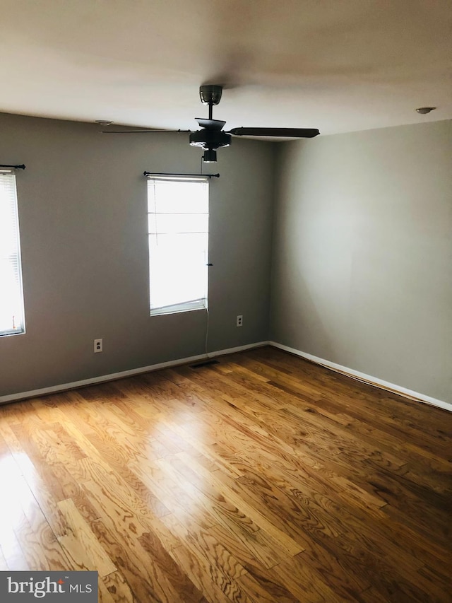 unfurnished room with baseboards, wood finished floors, and a healthy amount of sunlight