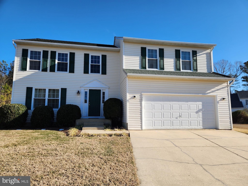 view of front facade with a garage, concrete driveway, and a front yard