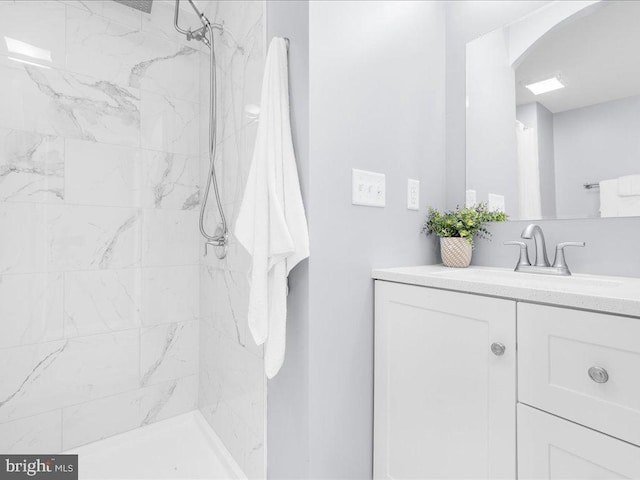 full bath with vanity and a marble finish shower