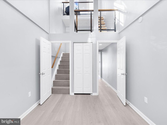 interior space with a towering ceiling, baseboards, and wood finished floors