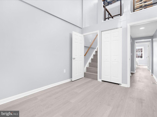 interior space with stairs, a high ceiling, wood finished floors, and baseboards