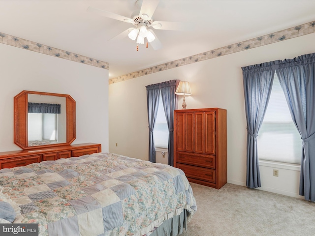 bedroom featuring light carpet, a ceiling fan, and baseboards