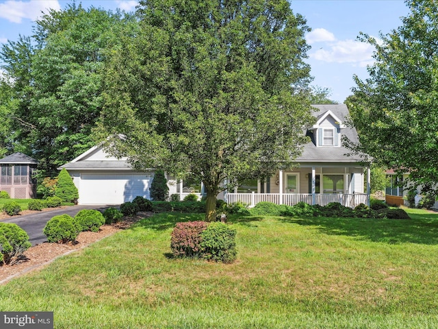 view of property hidden behind natural elements with aphalt driveway, a front yard, a porch, and an attached garage