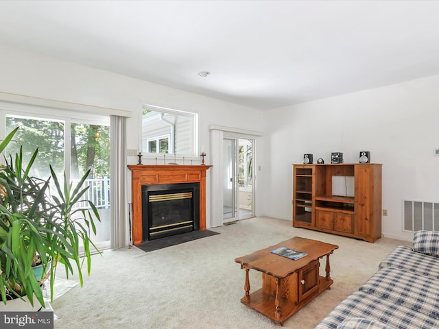 living area with a fireplace with flush hearth, visible vents, and light colored carpet