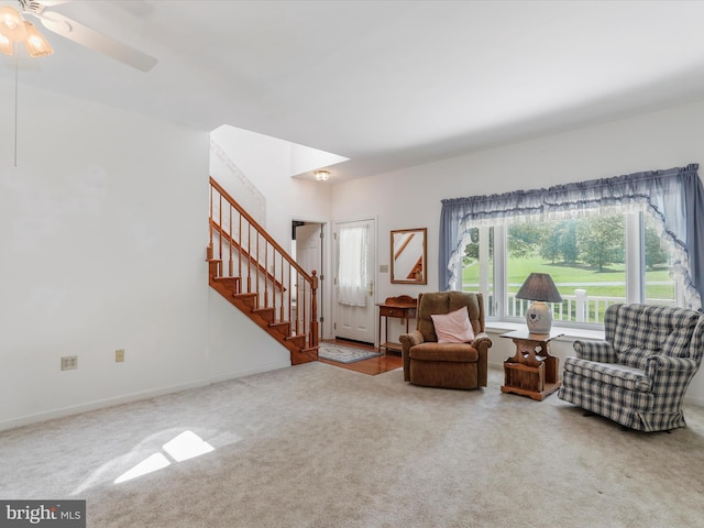 living area featuring ceiling fan, stairway, carpet flooring, and baseboards