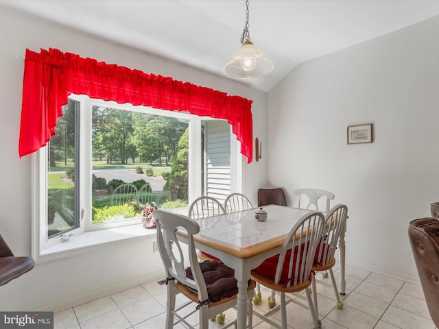 dining space featuring a wealth of natural light, light tile patterned flooring, and vaulted ceiling