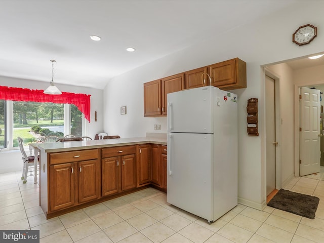 kitchen featuring decorative light fixtures, brown cabinets, light countertops, freestanding refrigerator, and a peninsula