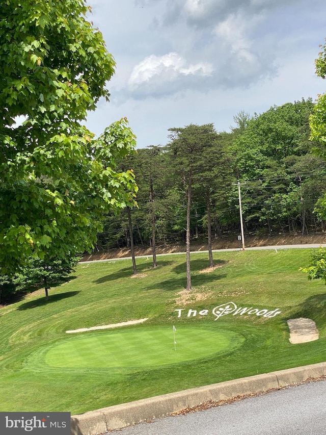 view of community featuring view of golf course and a yard