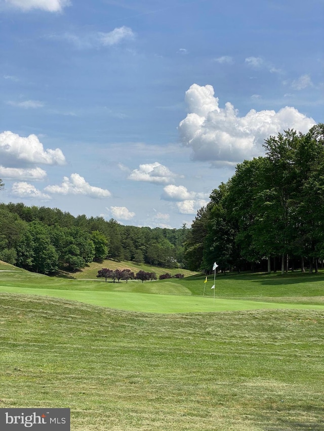 view of property's community with view of golf course and a lawn