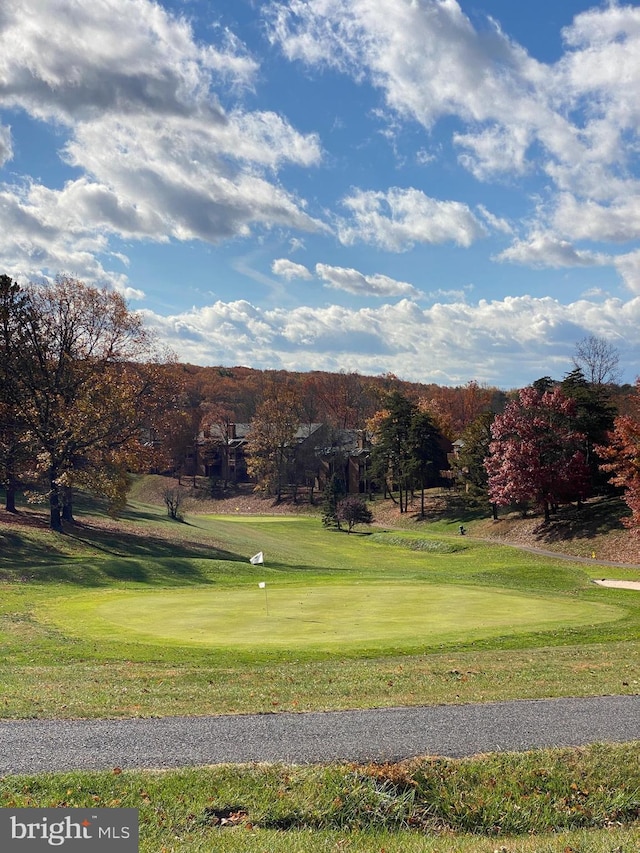 view of property's community with view of golf course and a lawn